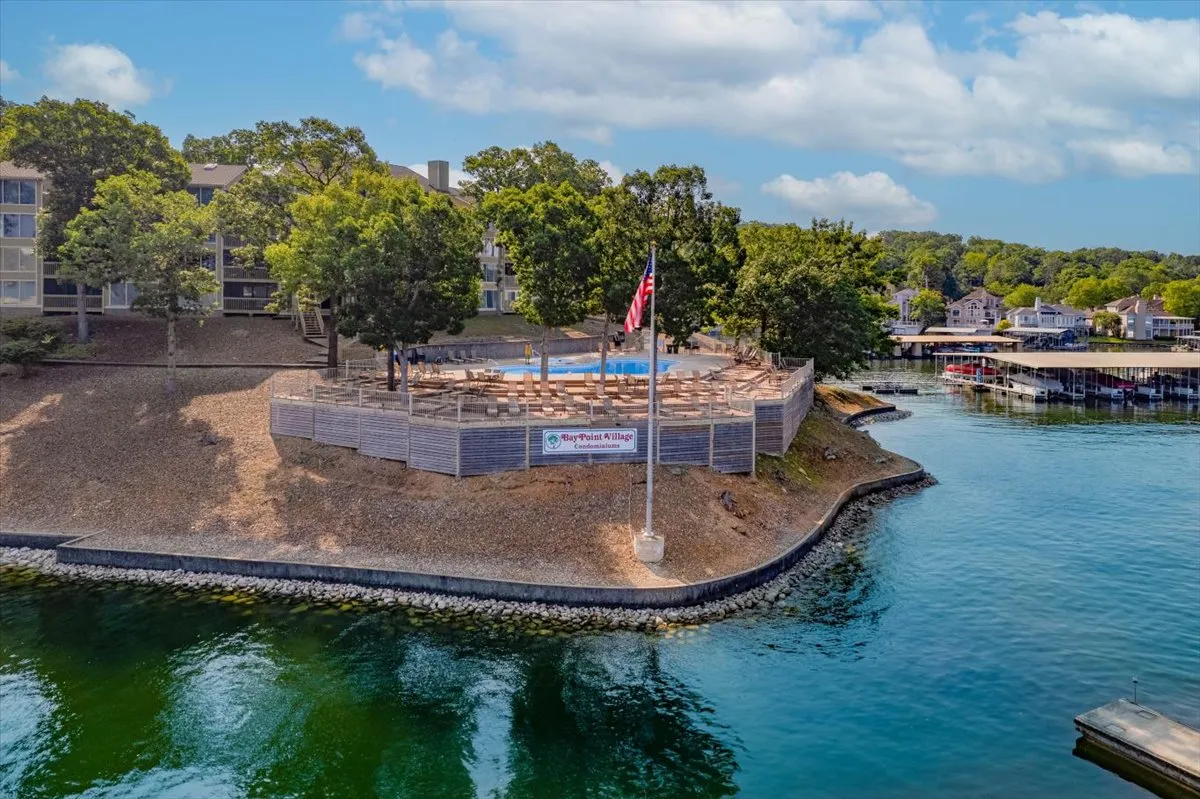 A wide waterfront view with a flagpole, dock, trees, and open sky. The expansive perspective showcases access to the lake and outdoor activities such as boating, fishing, and picnicking, while evoking a sense of freedom and exploration.