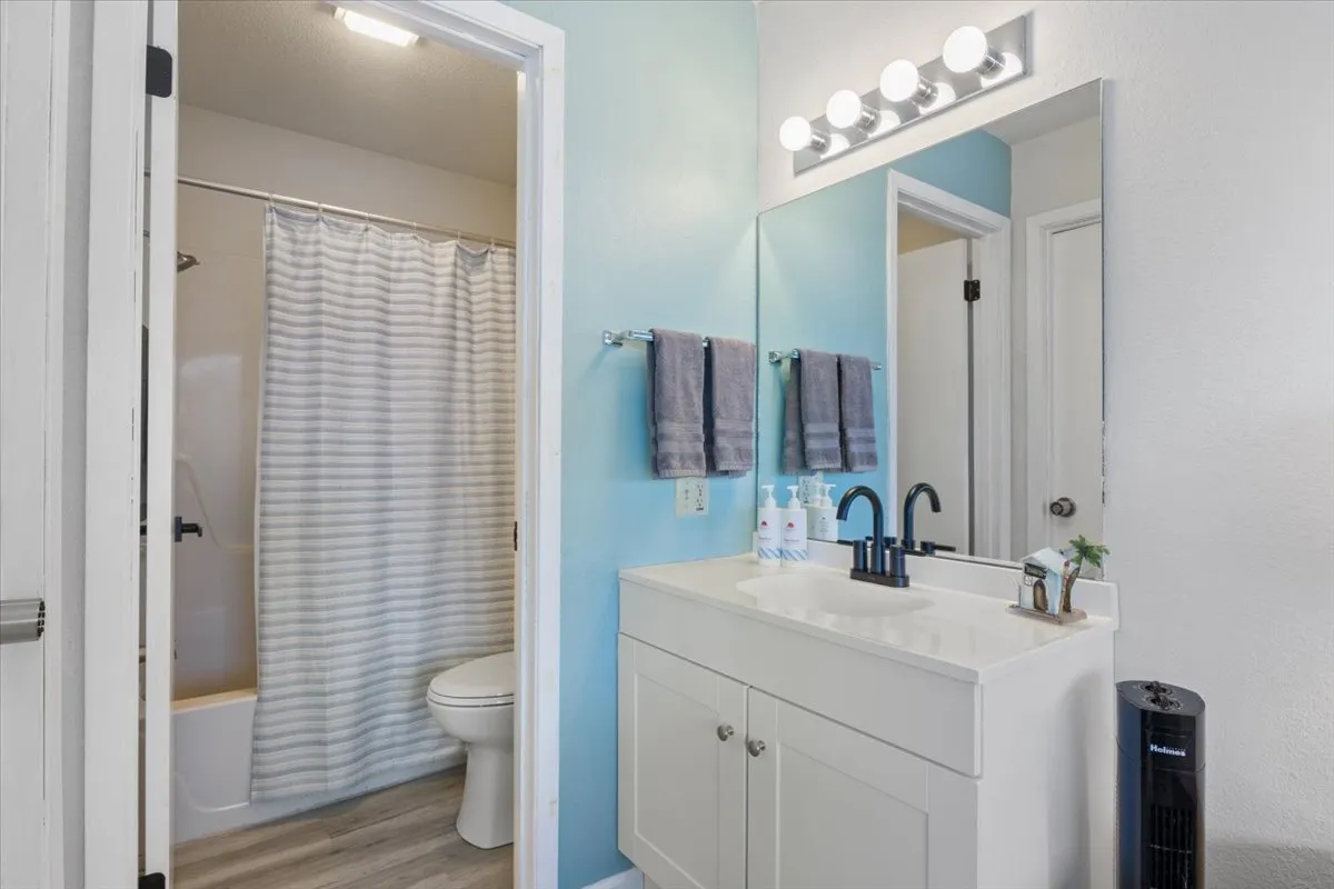 A modern, updated bathroom with a pristine vanity, wall-mounted mirror, and a spacious shower area. The lighting and clean design promote a sense of relaxation and self-care, with space for personal grooming.
