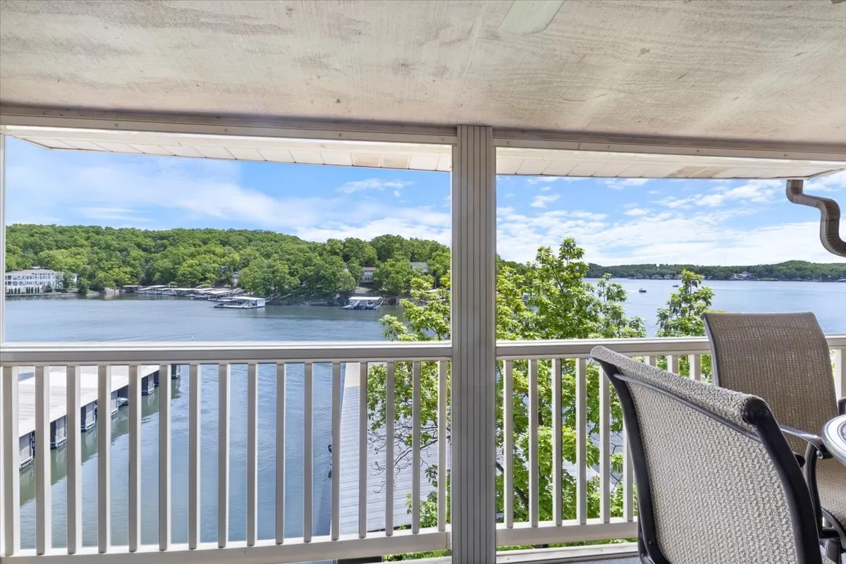 A serene view featuring the shimmering lake, lush green trees, and an inviting outdoor seating area. The tranquil setting suggests a perfect spot for unwinding after a day spent on the golf course, reflecting the retreat's lakeside appeal.