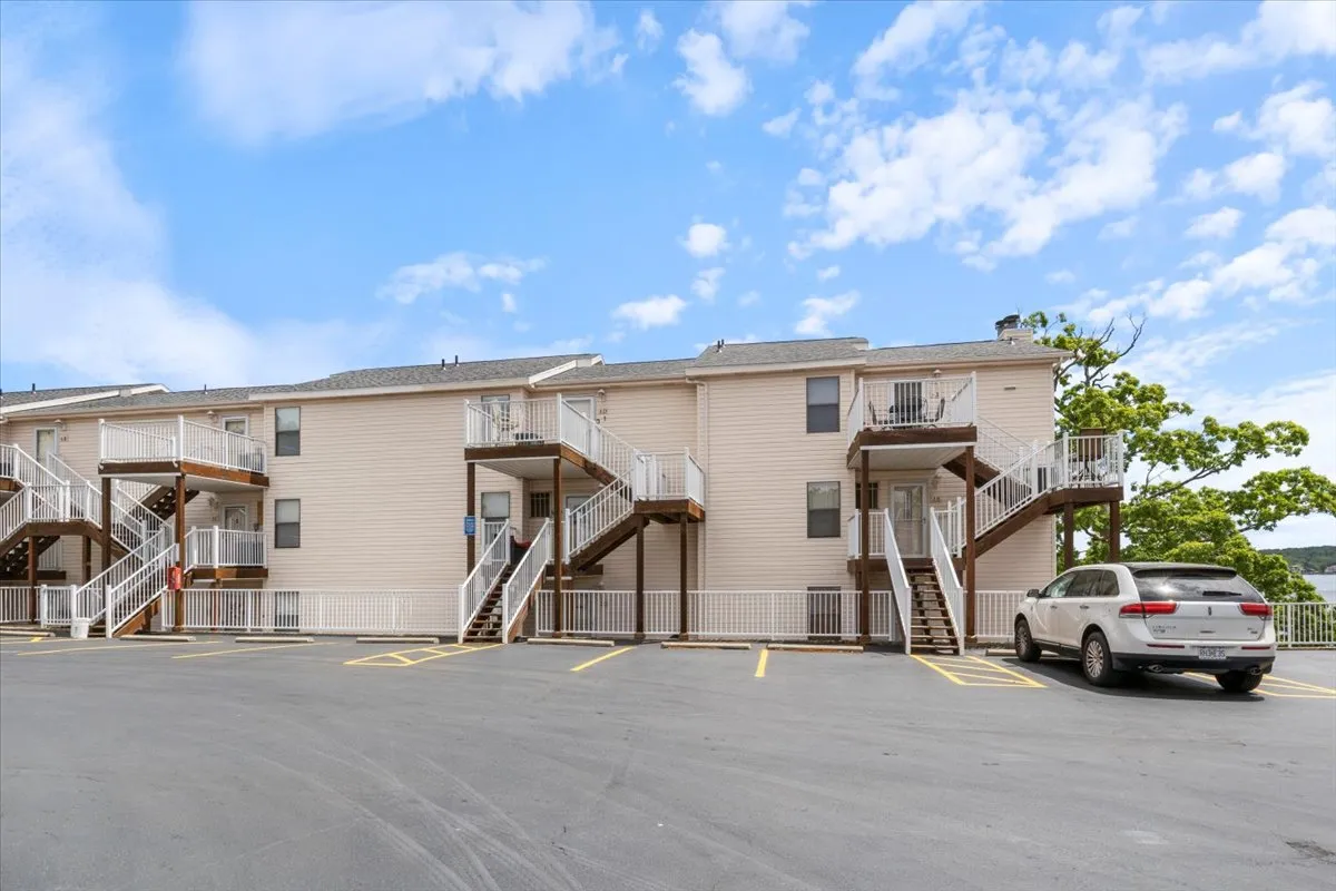 An exterior perspective featuring the condo's balconies and staircases with the parking area below. It conveys a welcoming, communal environment and hints at easy access to nightlife and local attractions.