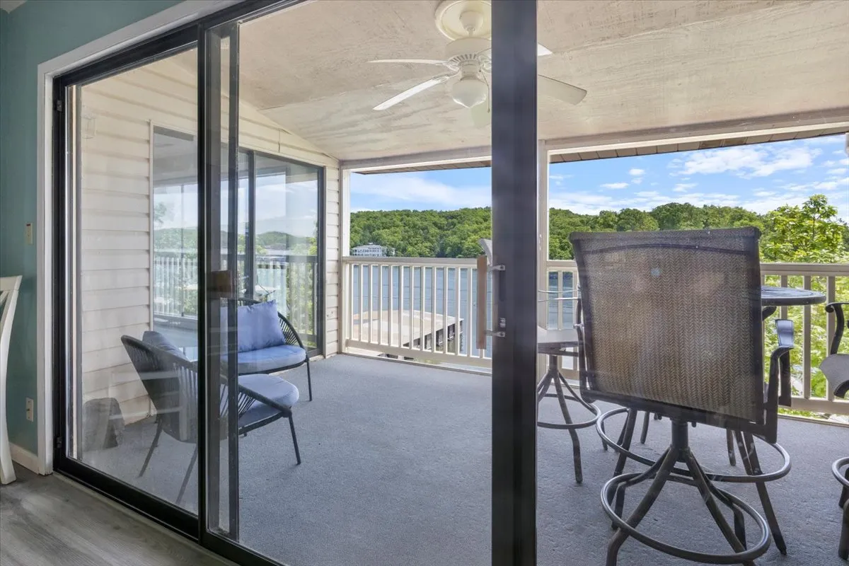 A view from a deck or balcony, showing inviting patio furniture that looks out onto the sparkling lake. The glass doors hint at the easy indoor-outdoor flow and the perfect spot to share wine while watching the sun dip below the horizon.