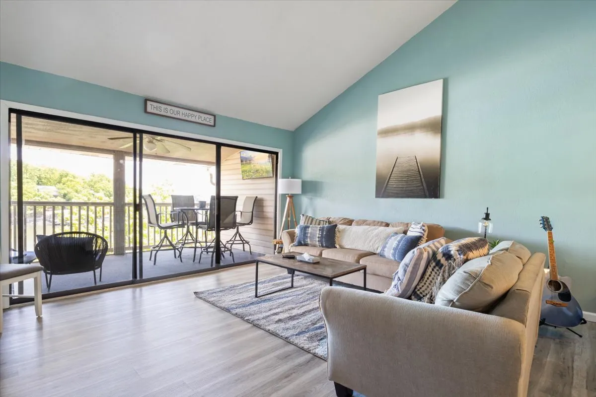An inviting living area with a cozy sofa, coffee table, and artwork, complemented by a view through sliding doors to the outdoors. The ample natural light and subtle blue accents set a romantic, relaxing mood perfect for winding down after a date night out.