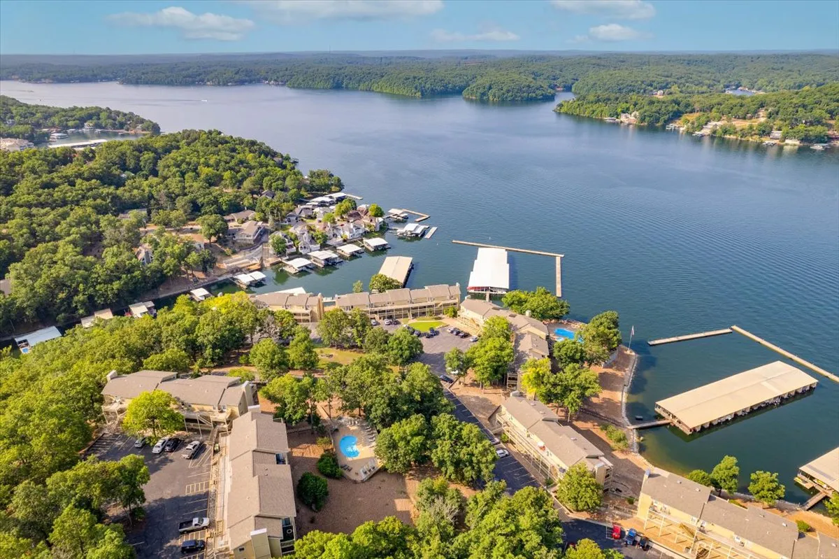 This image showcases a broad view of the lake, boathouses, surrounding greenery, and a swimming pool. The setting captures the heart of lake life, with water activities and a relaxed poolside atmosphere, perfect for group adventures.